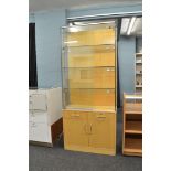 A display cabinet, having sliding glass doors to three glass shelf upper section over two drawers