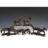 A collection of bronzed far eastern horses, in a variety of poses, six with ebonised hardwood