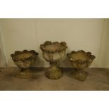 Three concrete plant pots, raised on columns and bases with foliate designs, the largest 60cm