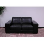 A modern black leather two seater sofa by Natuzzi, 172cm wide, 95cm deep, having fixed cushions