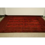 A 20th century Middle Eastern woollen Tekke style red and black carpet, 294cm by 205cm