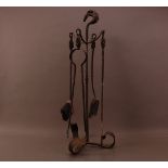 An early 20th century cast metal fire companion set, the stand with horse handle, on three scrolling