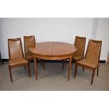 A c1970s G-Plan circular dining table and four chairs, having pull out mechanism with hinged leaf,