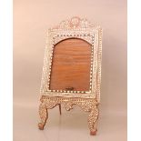 An early 20th century Indian hardwood and ivory inlaid mirror in Vizagapatam style, moulded top with