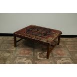 A first half 20th century upholstered footstool, 91cm by 77cm and 41cm high, with Caucasian rug