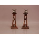 A pair of oak and pewter art noveau candlesticks by C. Hurren, pewter capitals, with finely carved