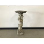 A modern concrete garden bird bath, 87cm high with a figure holding aloft a circular removable bath,