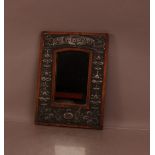 An early 20th century arts and crafts wood and pewter framed mirror, above the mirror inscribed '