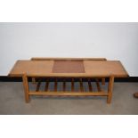 A 1970s teak coffee table by Remploy, having a pair of sliding panels to top opening to reveal