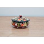 A Moorcroft pottery lidded pot, Rosehips' pattern, 2003, 8.5cm high and 13cm wide, in a retail box