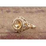 A 9ct yellow gold citrine and diamond cluster ring, the round cut in rubbed over setting