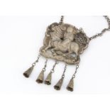 A Chinese white metal pendant, modelled as a sage upon a Buddhistic lion dog, with bell pendants, 48