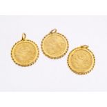 Three George V style yellow metal coins in 9ct gold pendant mounts, the half sovereign style coins