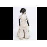 A primitive black cloth doll circa 1900, with white stitched rosette eyes with two-tone blue iris,