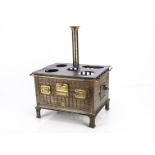 A doll's steel and brass gas cooker, with three ovens, brass towel and guard rail, chimney, cast-