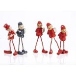 Four bisque long-legged policeman cake decorations, three in red and one blue, a similar man in