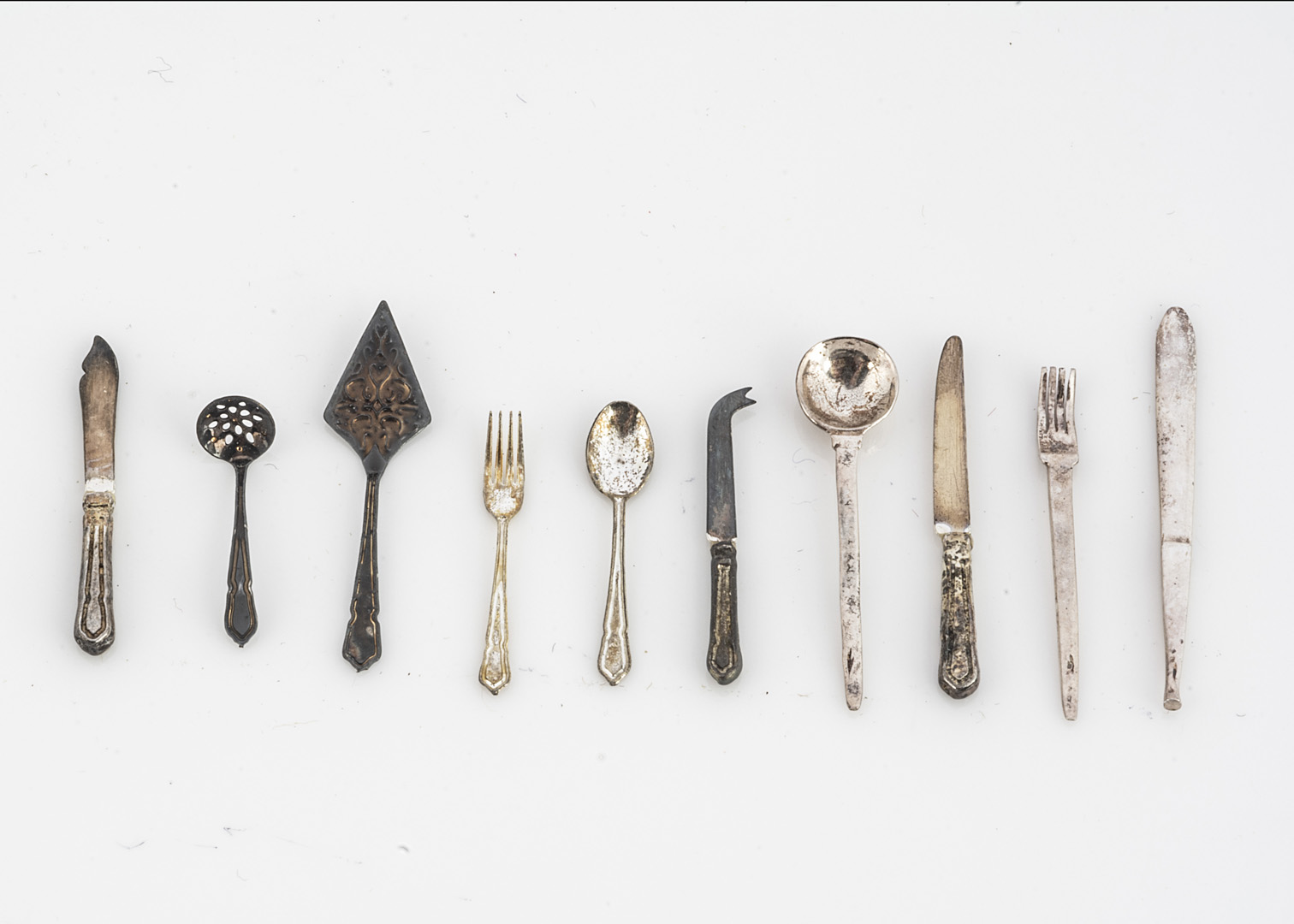 Modern dolls' house white metal cutlery, matching set comprising three sugar sifting spoons, cake