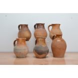 Five early 19th century partially salt-glazed terracotta jugs, and a handled ewer, of graduated