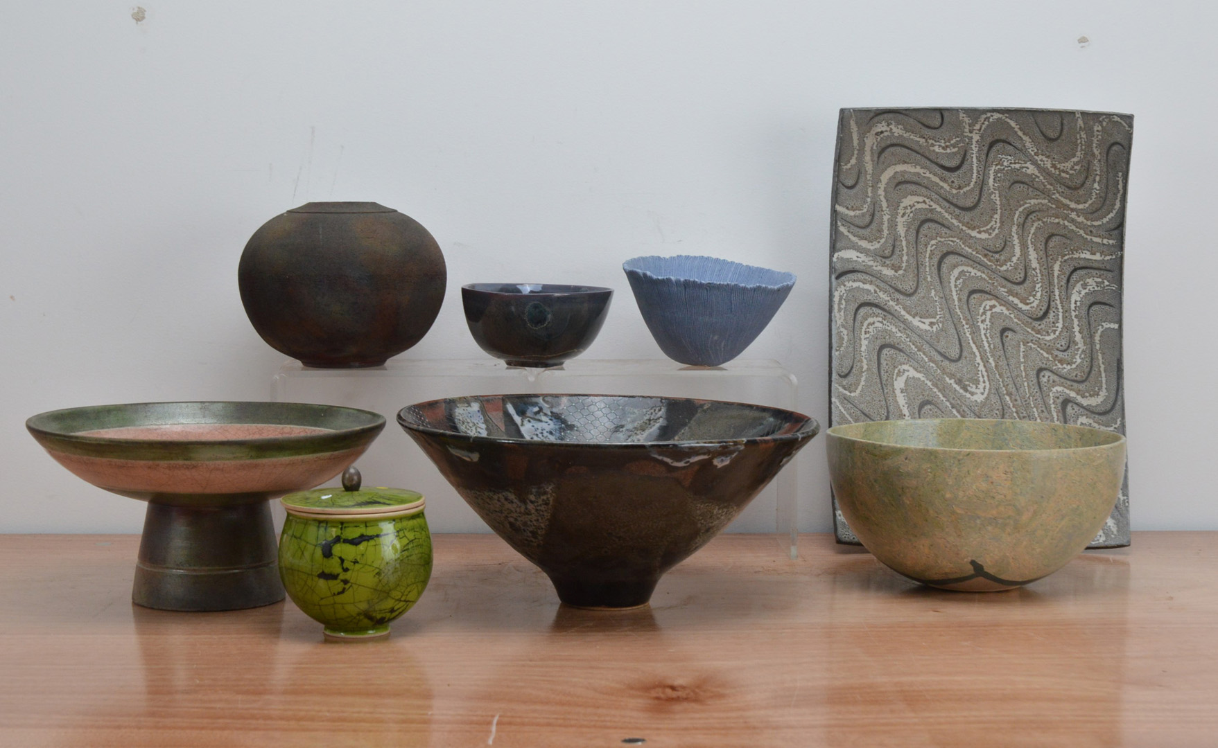 A collection of studio pottery, comprising a stoneware pot and cover with raku green and black glaze