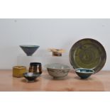 A collection of studio pottery, comprising a footed dish with a textured top with orange and brown