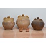 Three early 19th century twin handled graduated baluster terracotta ewers, partially salt-glazed,
