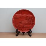 A 20th century Japanese Cinnabar Lacquer ornamental plate, 30.5cm wide with a hardwood stand.