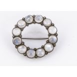 A moonstone and white metal circular brooch, the cabochon collet set circular stone alternately