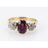 A three stone ruby and diamond claw set ring, the oval mixed cut central ruby in claw setting,
