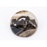 A 19th century agate hardstone circular brooch, of banded smoky quartz, with scroll and ring centre,