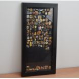 A large collection of mostly American Police pin badges, in a black display frame, the frame size