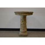 A 20th century carved stone bird bath, removable top, with carved edges, raised on a foliate and
