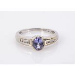 A 9ct white gold tanzanite and diamond ring, oval mixed cut set with channel set diamond