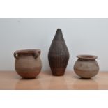 Three Islamic primitive terracotta vessels, comprising a tall baluster example 38cm high, a four
