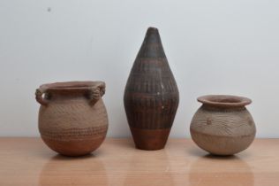 Three Islamic primitive terracotta vessels, comprising a tall baluster example 38cm high, a four