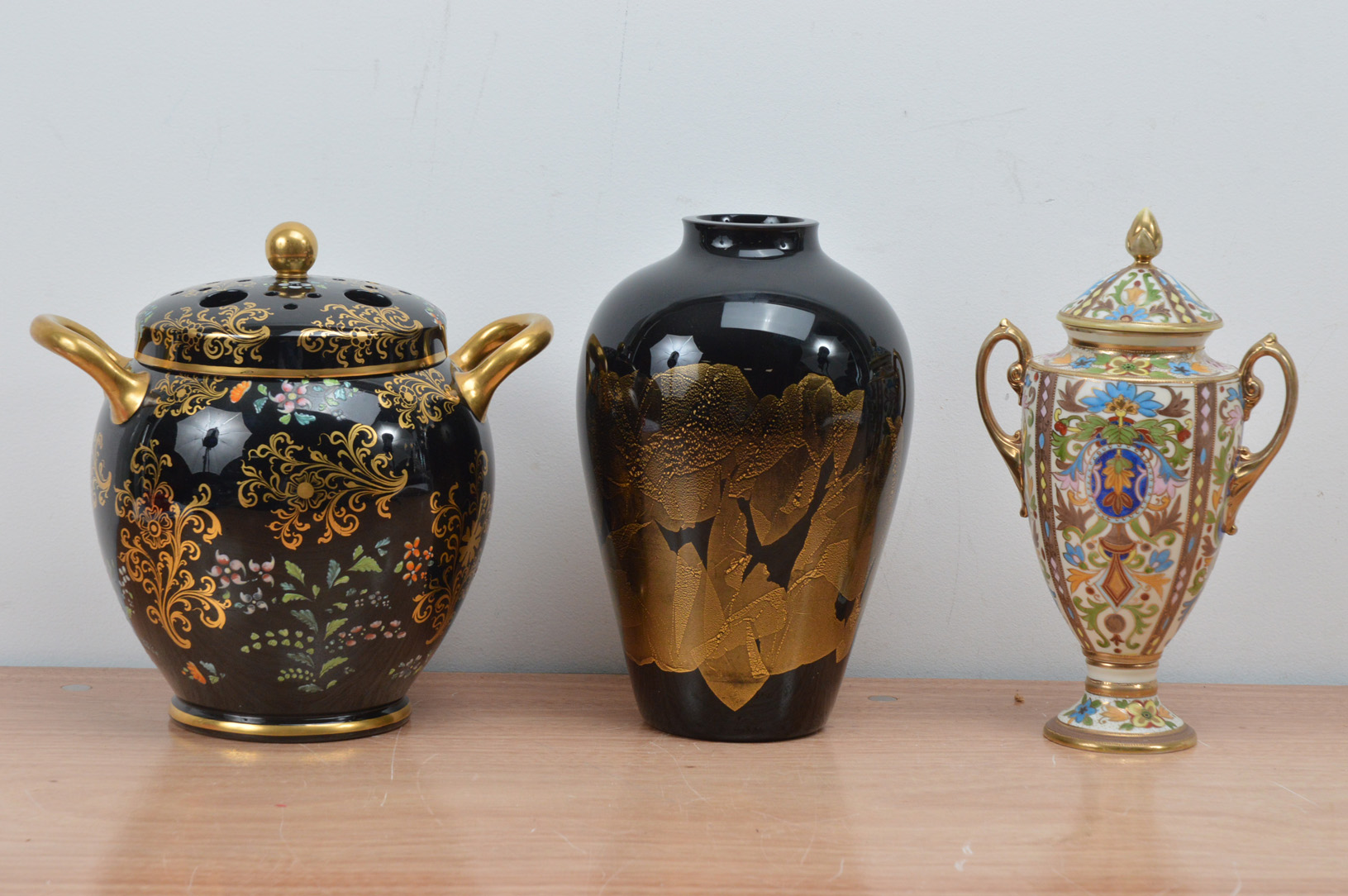 A 20th century porcelain twin handled vase, heightened gilt on a black ground with cover 24cm