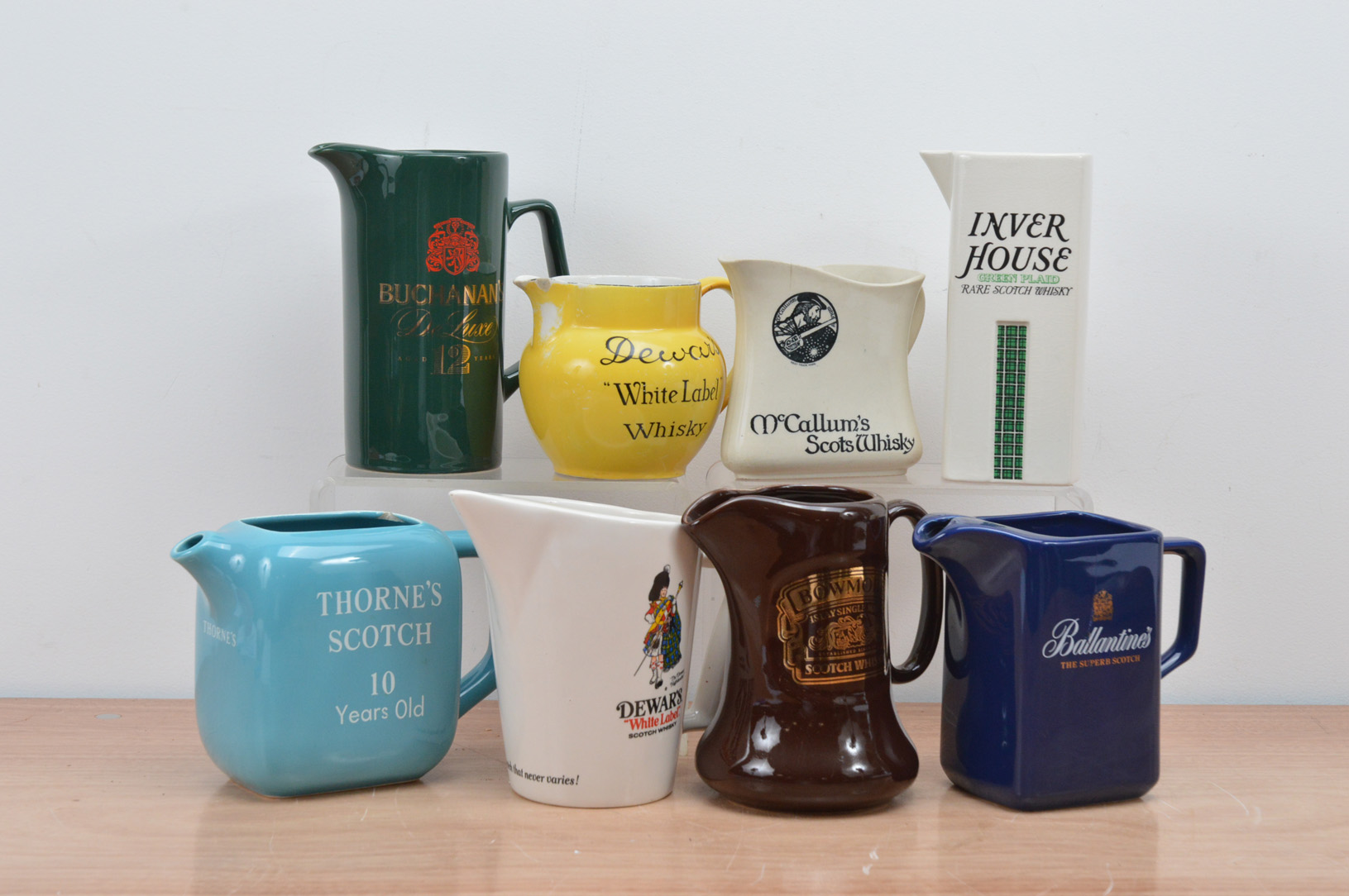 A collection of eight ceramic branded water jugs, comprising two Dewar's, Bowmore, Inverhouse,