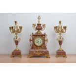 A late 19th century and later French red marble mantle clock garniture, the dial with Arabic