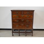 A George II and later walnut feather and crossbanded chest on stand, two short drawers over three