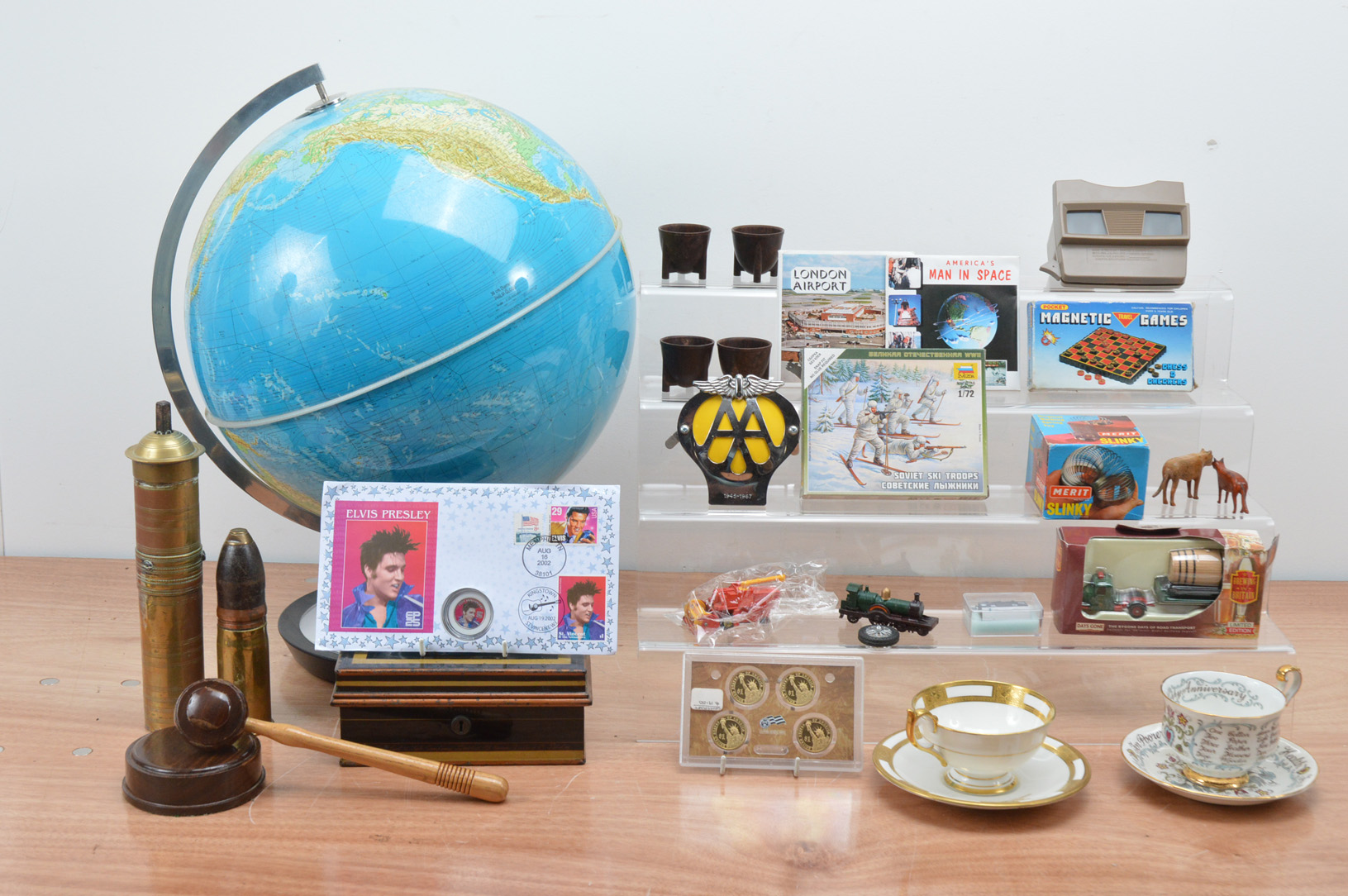 A large collection of collectables, including a modern globe, a shell, coin covers, paragon and