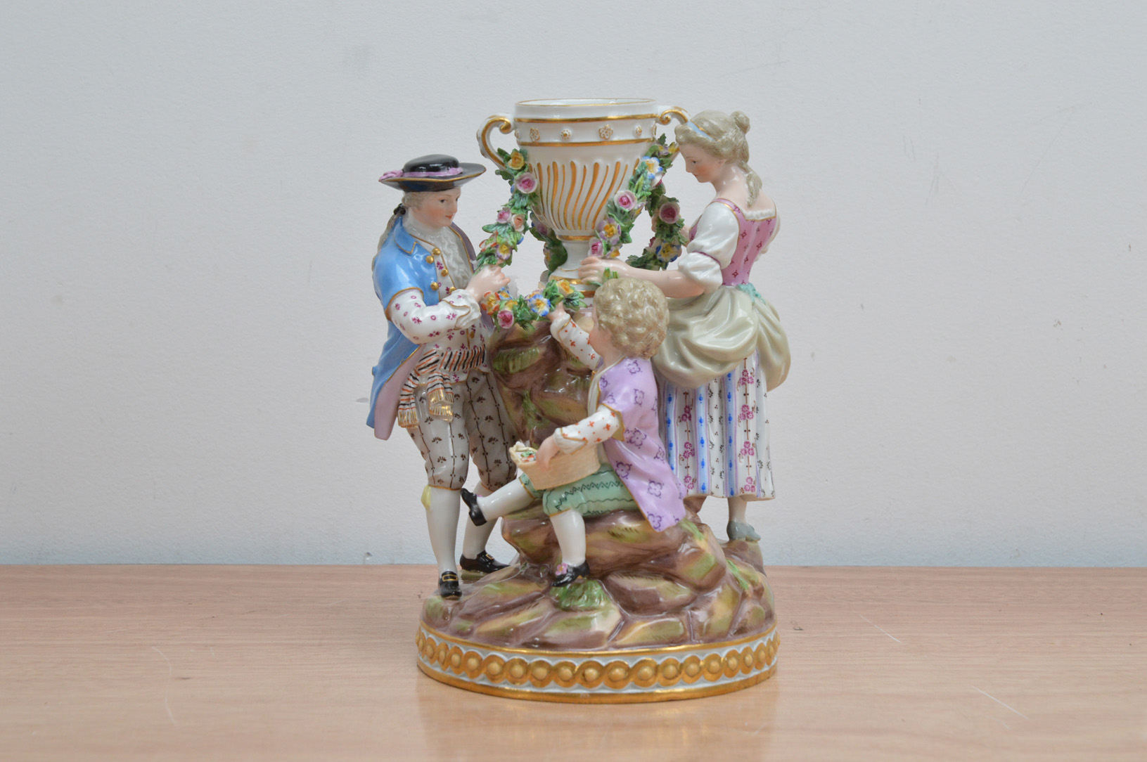 A 19th century Meissen porcelain figural group, of a man, woman and child surrounding a twin handled