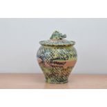 A studio pottery stoneware jar and cover, with a multi coloured design, the lid with a crocodile