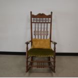 An early 20th century oak arts and crafts rocking chair, carved splats, green upholstered seat