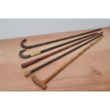 Five early 20th century and later walking sticks, including a red lacquer example, all with