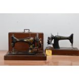 Four antique sewing machines, two Singer examples, two with locked wooden covers, all with damage,