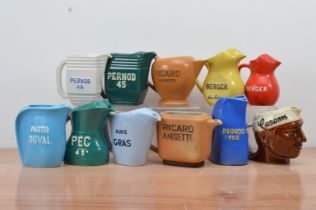 A collection of eleven ceramic continental water jugs, including Pernod, Berger Pastis, etc, of