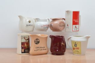 A collection of eight ceramic branded water jugs, comprising Johnnie Walker, The Real Mackenzie, Old