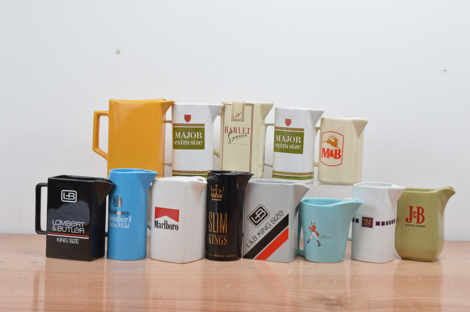 A collection of 13 cigarette branded ceramic water jugs, including Marlboro, Silk Cut, Hamlet,