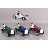 Four ceramic racing car models, one of silver Mercedes, the others of a different style in blue,