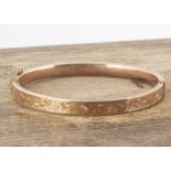An oval 9ct gold bangle, with engraved top, hinged, 5.4 cm by 6.2 cm, 7.8g