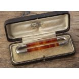 An agate and silver oval open worked brooch, the faceted banded columns united by engraved white